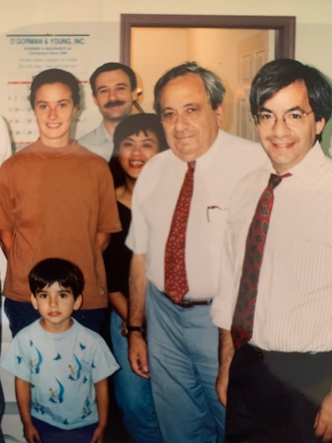 At the family business: Benjamin as a child in front, Abe in the middle wearing a tie, and Hal on the right wearing a tie, with others at the office.